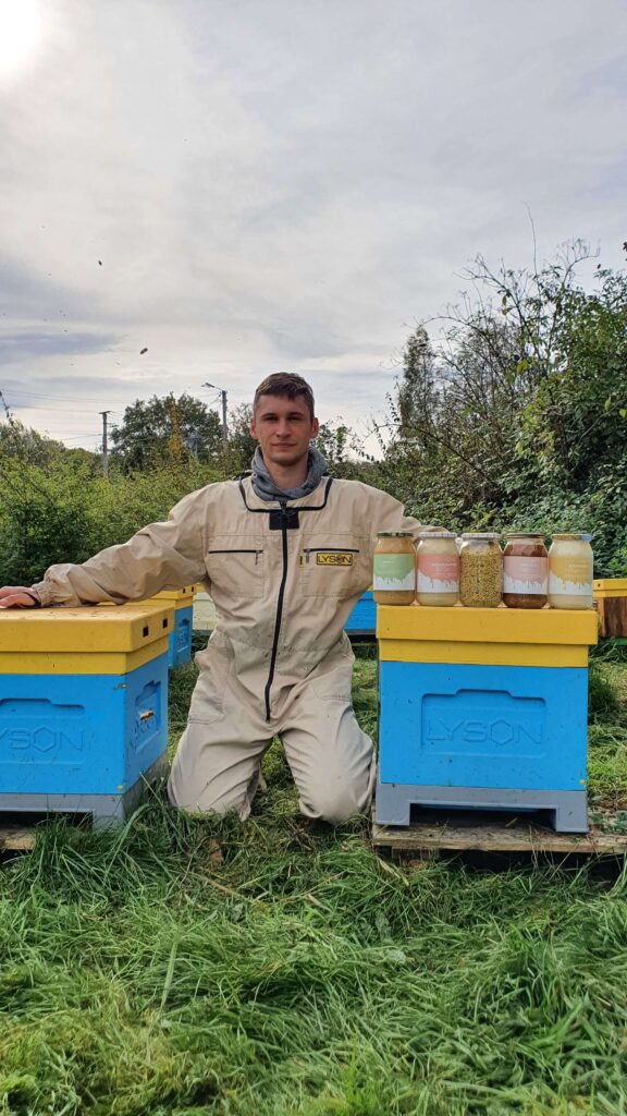 Łukasz właściciel pasieki obok swoich uli